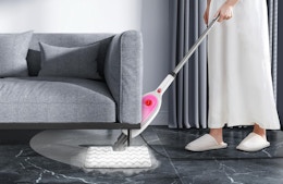 a person using a steam mop under a couch