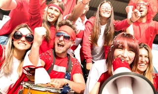 Young amateur football supporter fans cheering with flags watchi
