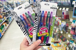 hand holding two packs of zebra pens