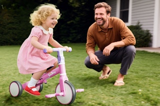 father watching child ride their bike
