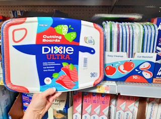Dixie Ultra Disposable Cutting Boards held in front of shelf at Walmart