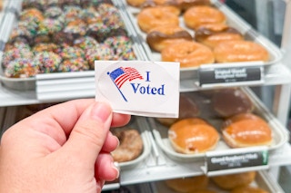 someone holding their I Voted sticker at krispy kreme