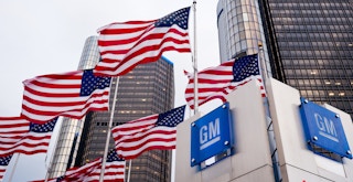 A GM sign with American flags on flag poles surrounding it
