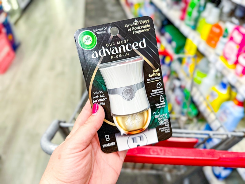 person holding an air wick advanced oil warmer over a cart