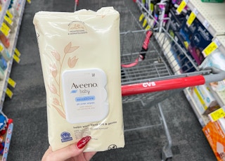 hand holding aveeno baby wipes in front of cvs cart