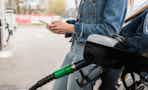 woman looking at phone while filling up car with gas