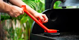 a person using a steam grill brush