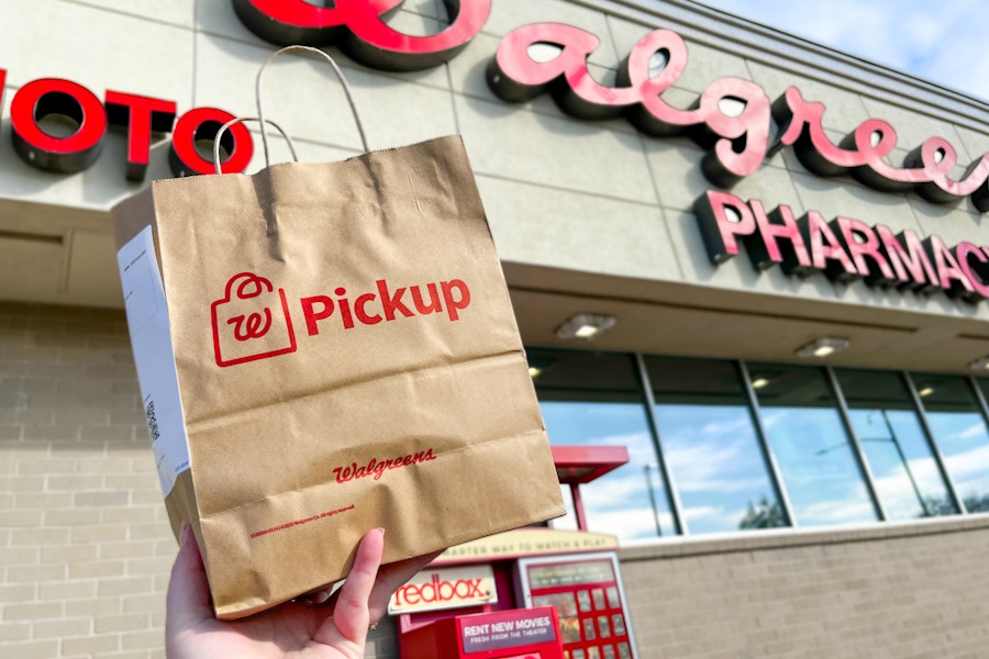 someone holding up a Walgreens pickup bag outside of a Walgreens