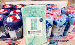 A hand grabbing a The Big One Oversized Beach Towel off a shelf at Kohls