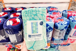 A hand grabbing a The Big One Oversized Beach Towel off a shelf at Kohls