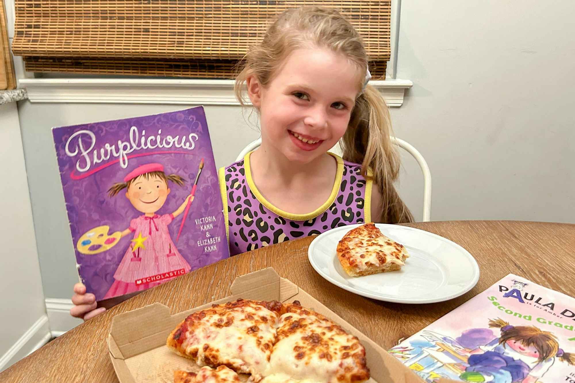 A little girl with books and a personal pizza from Pizza Hut