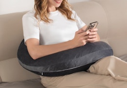 a person sitting on a couch with a reading pillow