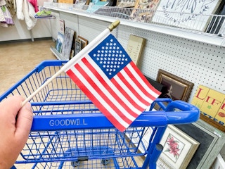 an american flag being held in front of goodwill cart 
