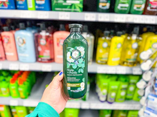 hand holding bottle of herbal essences shampoo in walmart aisle