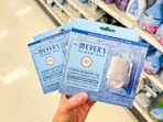 hand holding two packs of mrs meyers diffuser kits in target aisle