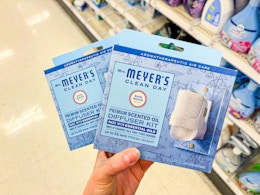 hand holding two packs of mrs meyers diffuser kits in target aisle