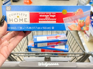 hand holding complete home bags in front of shopping cart