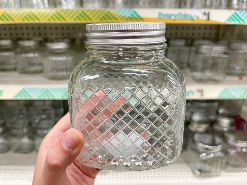 A glass jar with a list, with a geometric pattern on the outside.