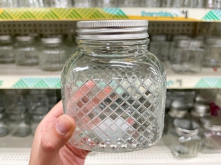 A glass jar with a list, with a geometric pattern on the outside.