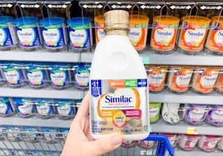 32 oz similac pro sensitive liquid formula held up in front of other formulas