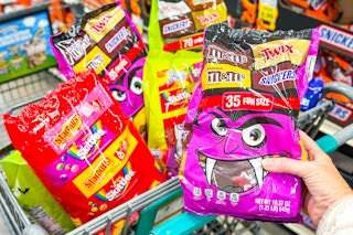 a person holding a bag of candy in front of a kroger cart 