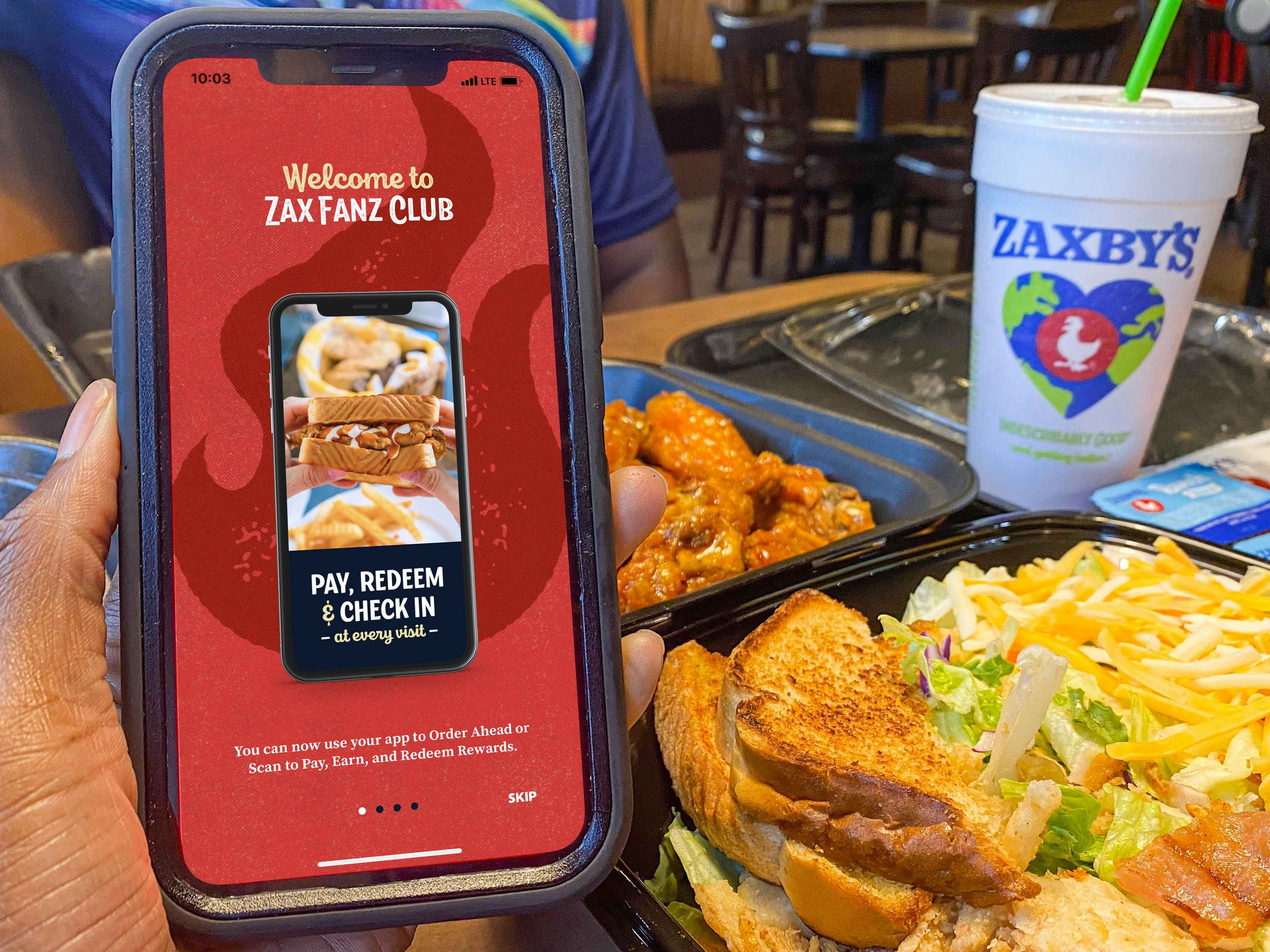 a cellphone being held with zaxby app on screen near food 