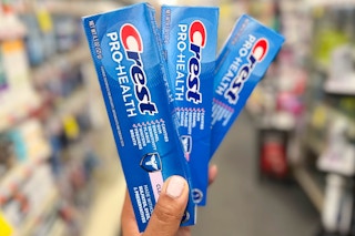 hand holding three tubes of crest pro health toothpaste