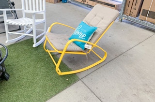 yellow metal rocking chair with tan cushion sitting in walmart garden center