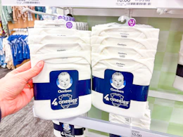 holding a pack of gerber baby bodysuits in front a target shelf