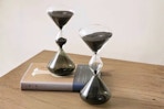 Lifestyle image of the Glitzhome Hourglass Sand Timers on table with book