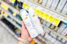person holding 2 dove whole body deodorant sprays