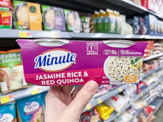 A package of one minute rice held out by hand in front of store shelves.