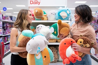 two people holding up squishmallows in a target