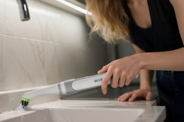 Woman using the WORKPRO Cordless Grout Brush Set in her kitchen.