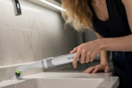 Woman using the WORKPRO Cordless Grout Brush Set in her kitchen.