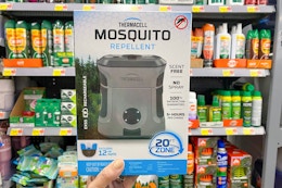 person holding a thermacell mosquito repeller in front of a shelf