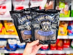 hand holding two packs of rare breed dog treats in walmart aisle