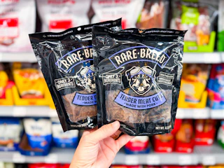 hand holding two packs of rare breed dog treats in walmart aisle
