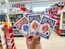 a hand holding two packs of playing cards in a store