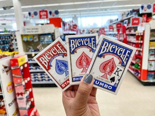 a hand holding two packs of playing cards in a store