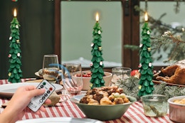 Person controlling the ZLCYFJIXV Flameless Christmas Tree Candles with Remote on a dinner table.