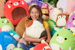 a girl sitting in a pile of squishmallows