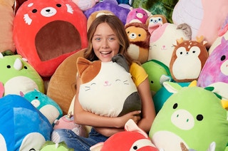 a girl sitting in a pile of squishmallows
