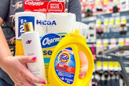 person holding colgate, dove, tide, and charmin products