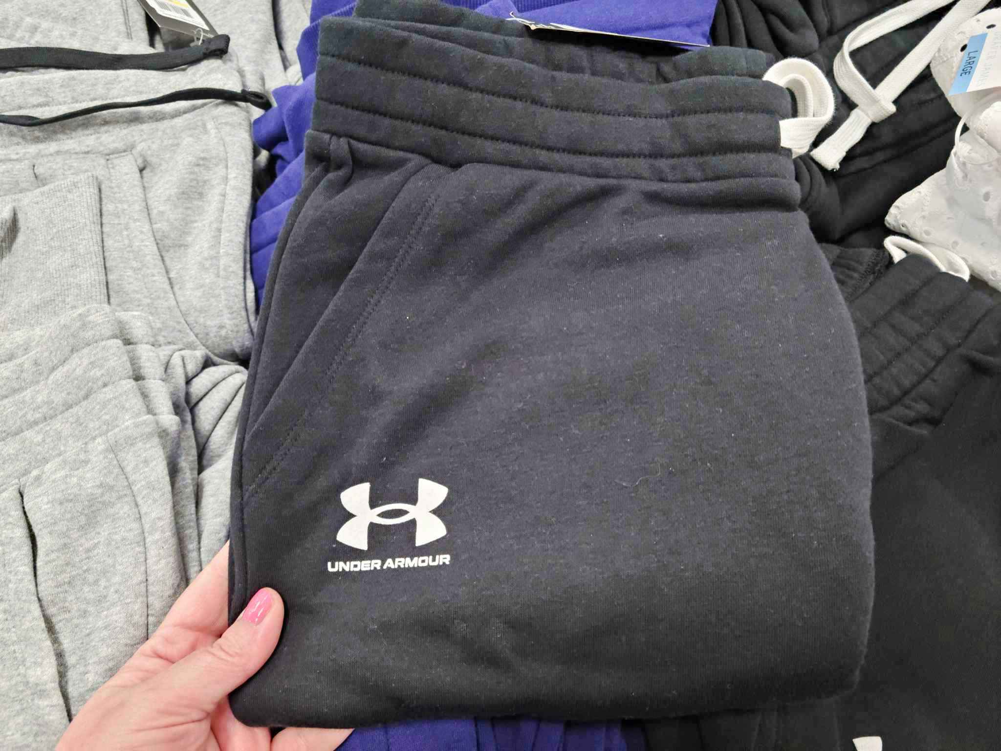 person grabbing a pair of black under armour joggers