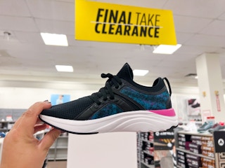 someone holding up a pair of women's running shoes