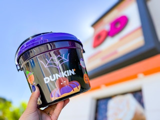 a person holding up a dunkin donut halloween bucket