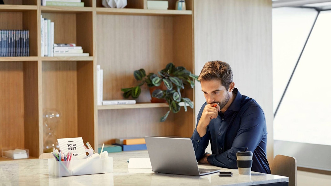 Man looking at his laptop while sitting at a desk