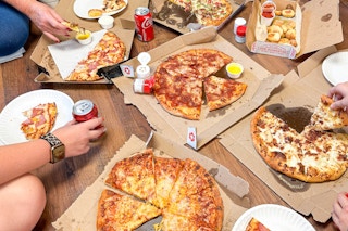 a group of people eating pizza from dominoes