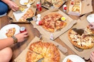 a group of people eating pizza from dominoes